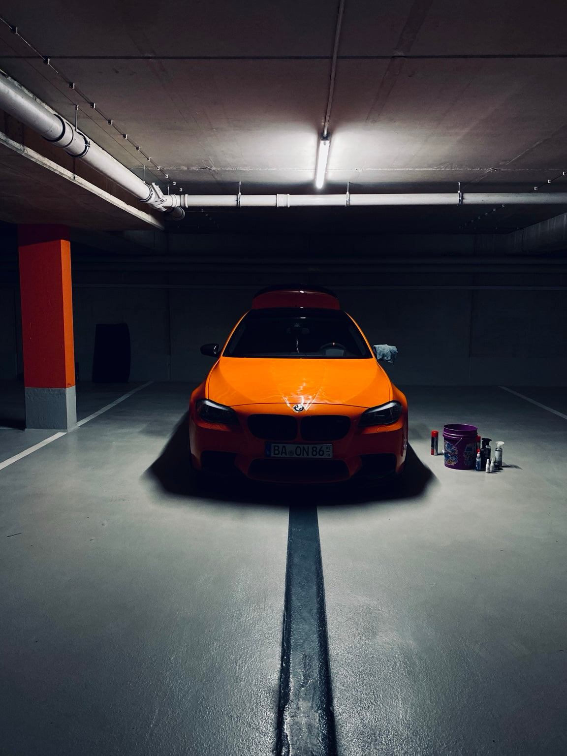 BMW M5 Fire Orange mit Autopflegezubehör in der Garage